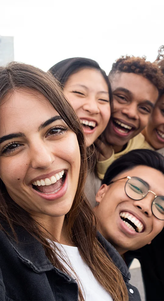 Group of young friends smiling and taking a selfie, representing joy, connection, and recovery support at San Diego Wellness Center.