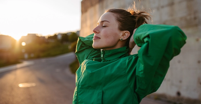 Young woman in green jacket relaxing outdoors after detox treatment at San Diego Wellness Center, embracing peace and recovery.