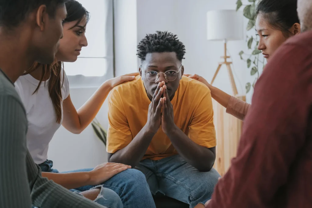 Man receiving emotional support from peers during group therapy session for addiction recovery at San Diego Wellness Center.
