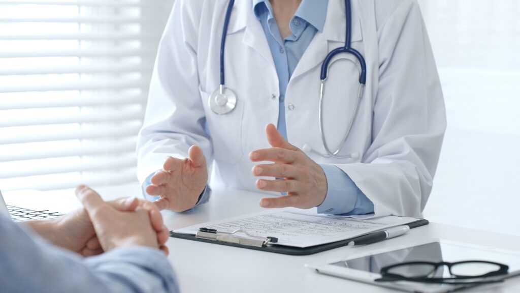 Doctor consults with a patient about Medication-Assisted Treatment (MAT), with a clipboard and medical forms on the desk.