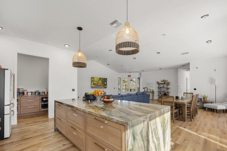 Beautifully spacious Kitchen and Dinning area of the SD-Wellness Drug Rehab Facility in Ironwood, CA. Luxurious marble counter tops and boho lampshades. High ceiling, white walls, and Woodend floors with a blue couch