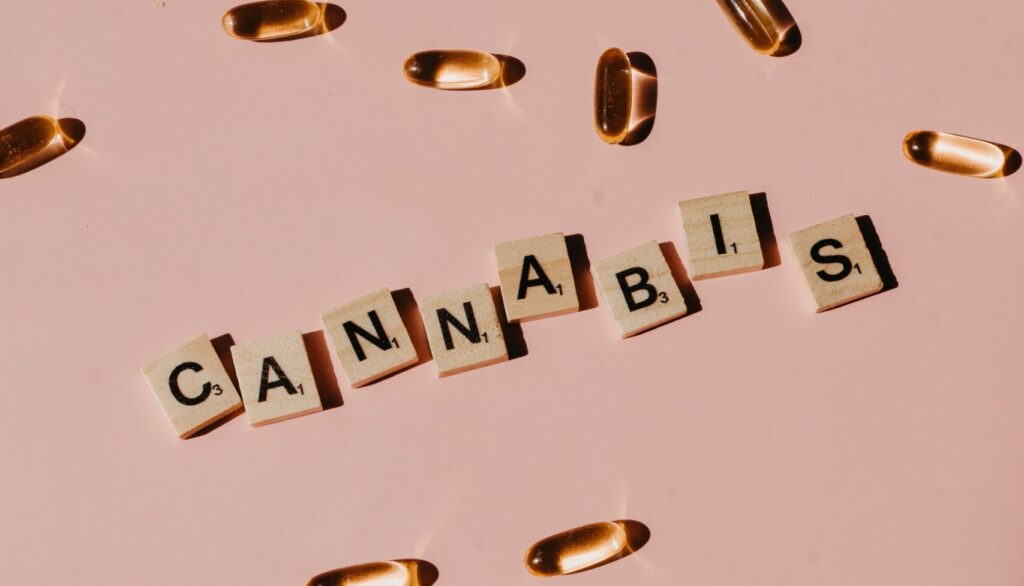 Cannabis spelled out by each letter on a pink background and medication pills scattered around the words. Marijuana Detox available at San Diego Wellness Center.