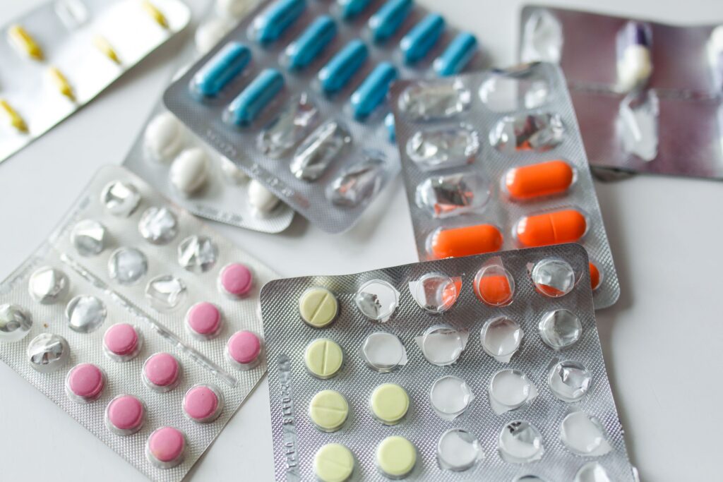 Blue, orange, pink, and yellow pills in a pill pouch. addiction recovery available at San Diego Wellness Center.