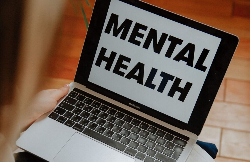 mental health in bold black letters with a white background on a laptop screen. Addiction Recovery at San Diego Wellness Center.
